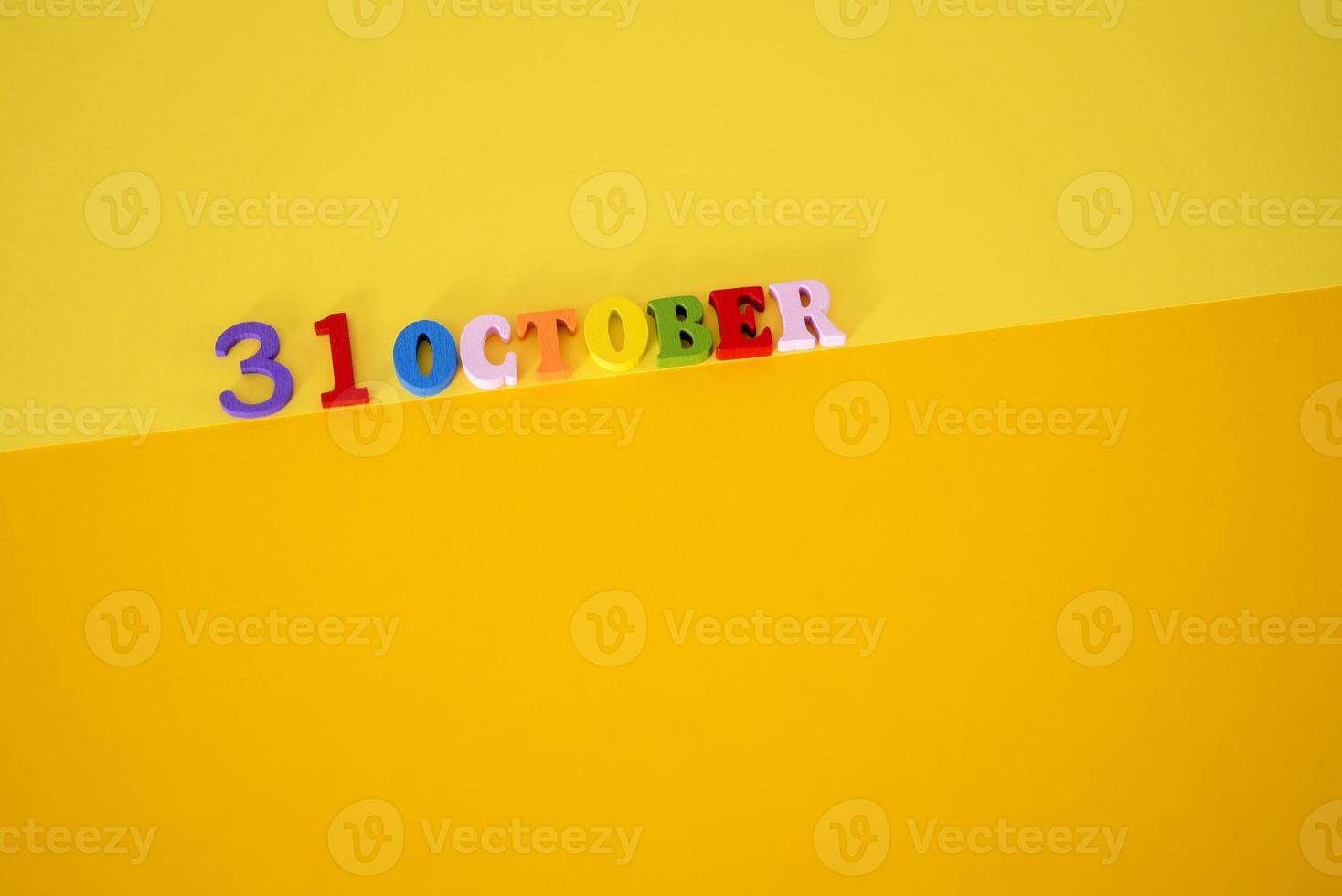 October 31 on a yellow, paper background with wooden and multicolored letters with space for text. photo