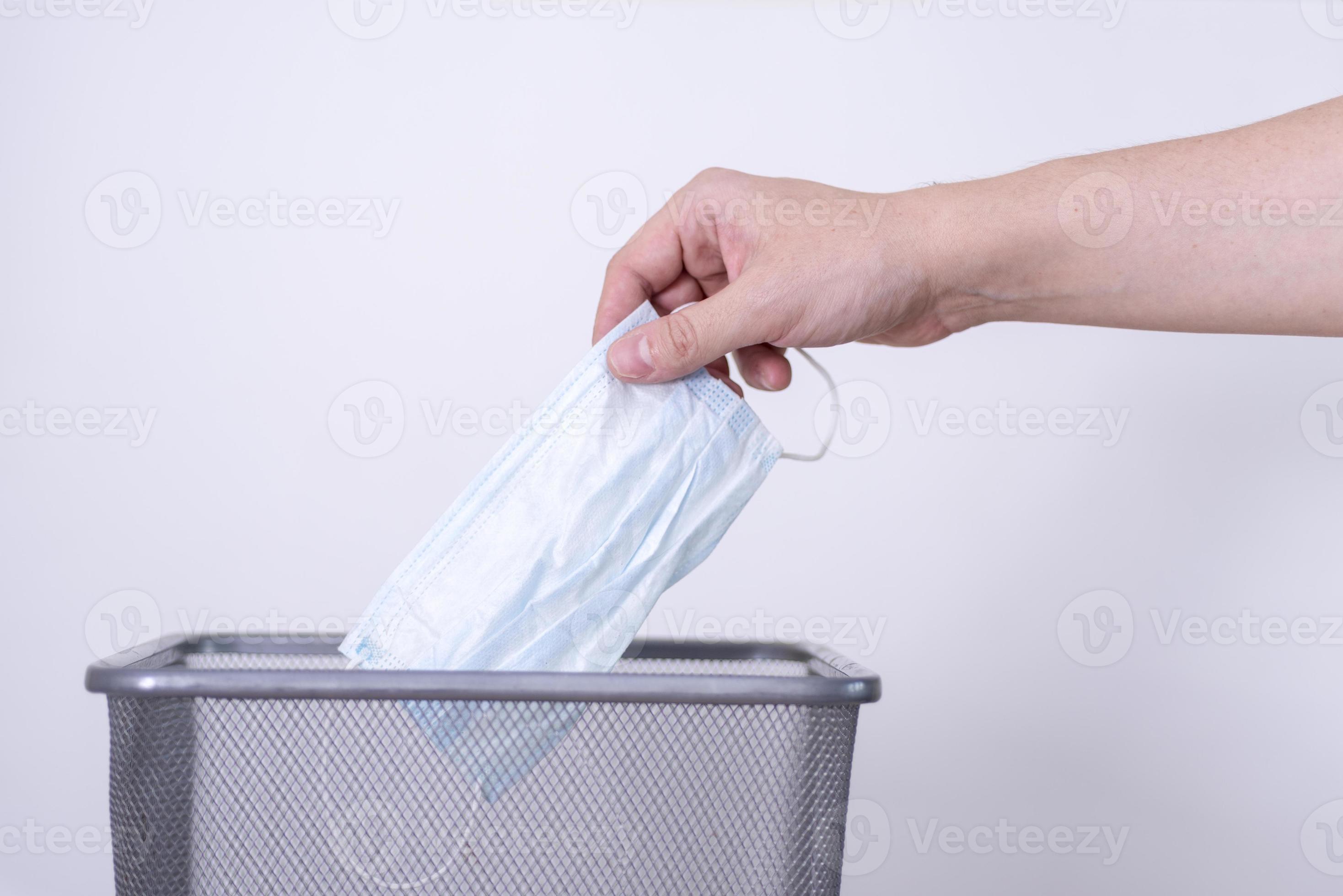 A man's hand throws a used medical mask into a trash can. 10655085 Stock Photo at Vecteezy