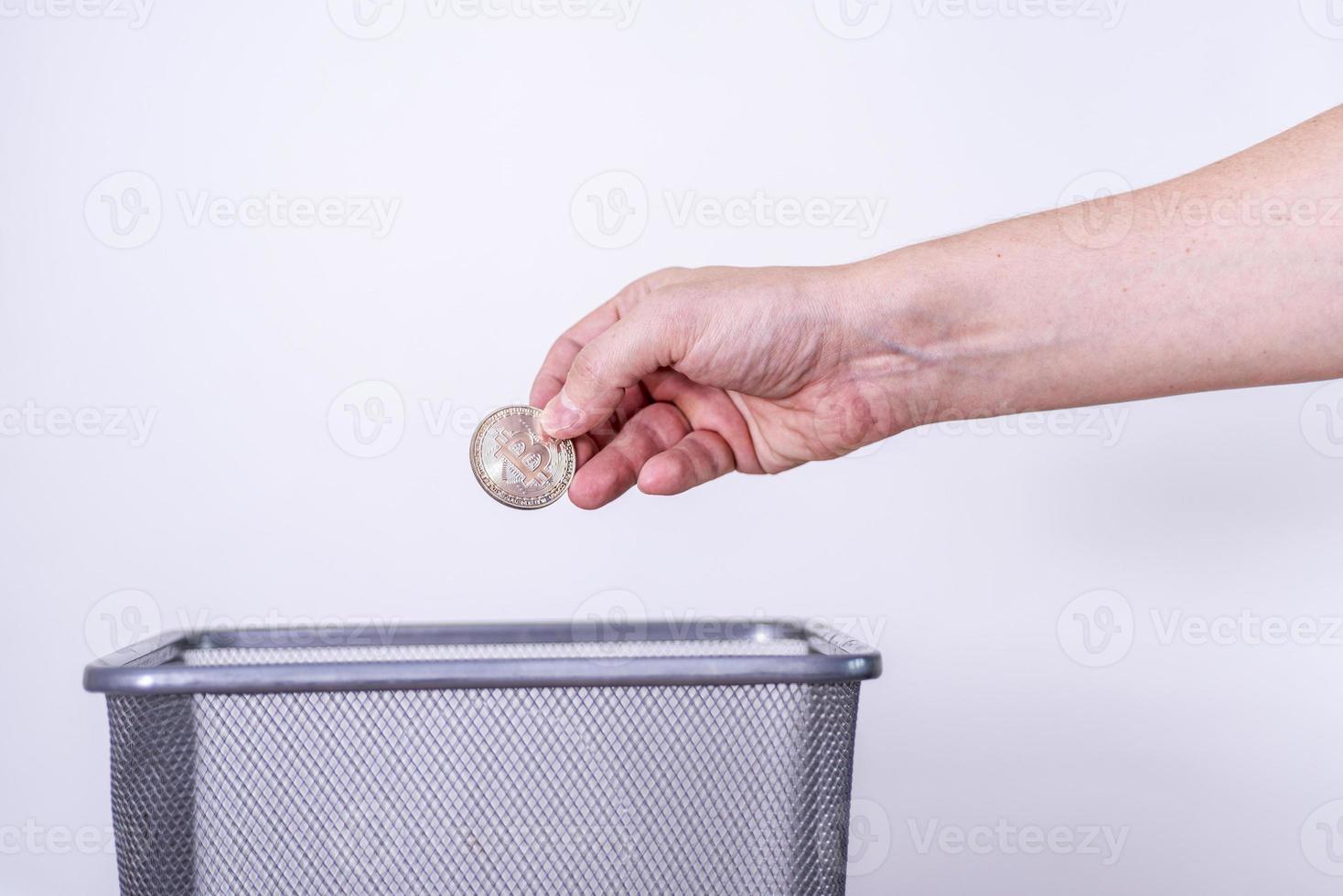 hand gettting out bitcoin in trash container. photo