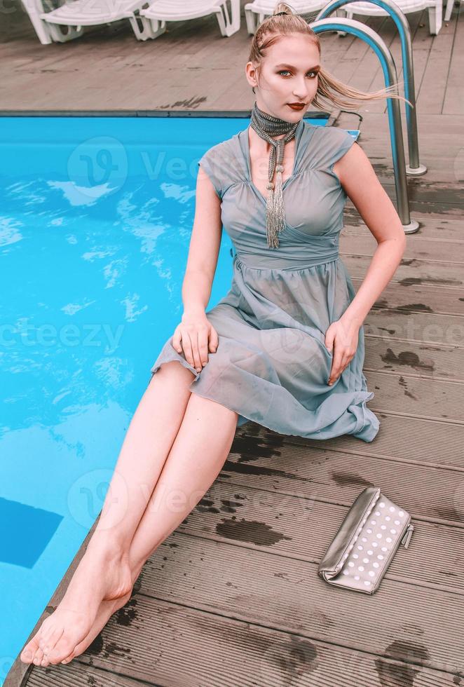 hermosa mujer en vestido de cóctel gris tendido cerca de la piscina foto