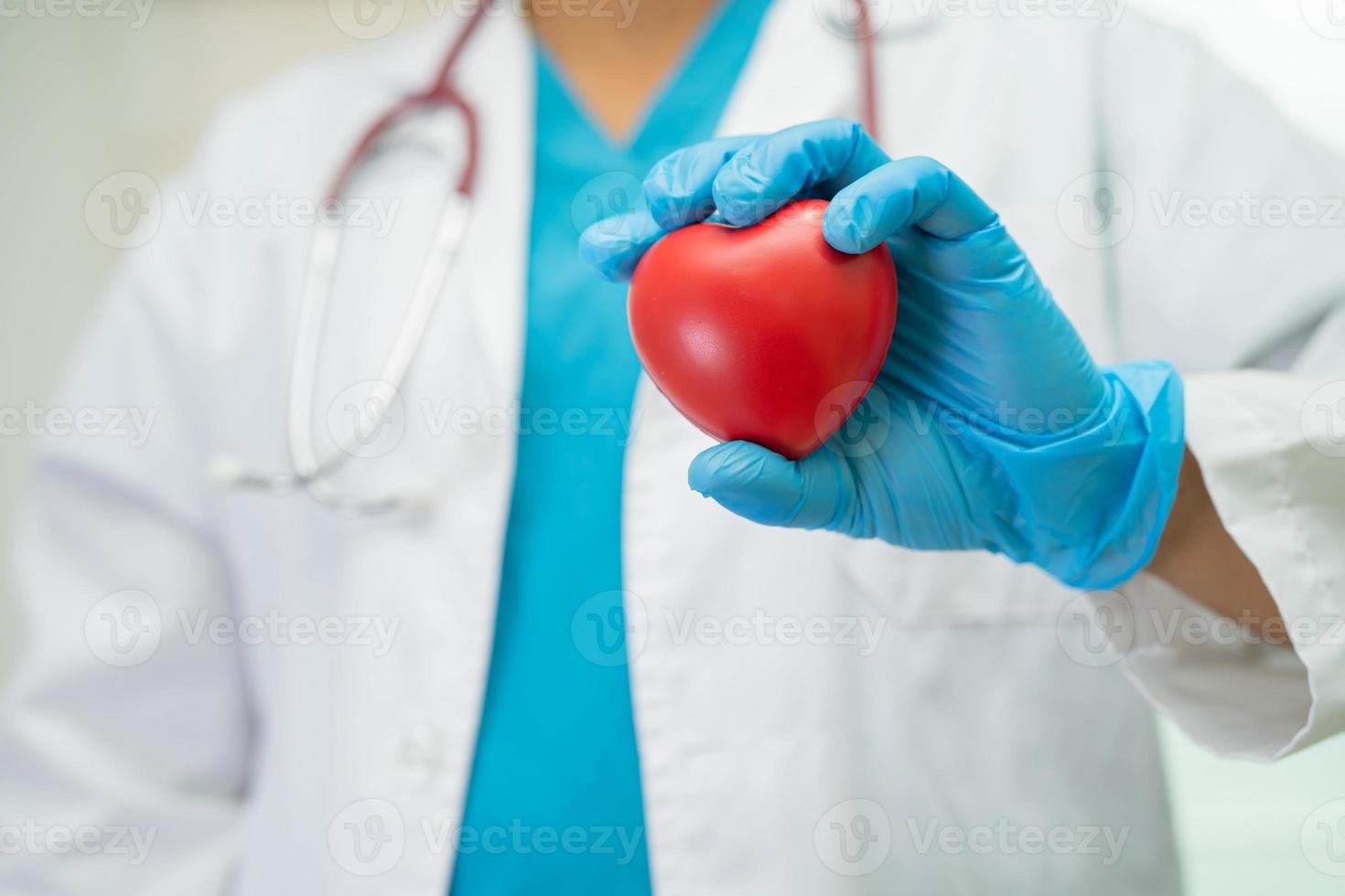 Doctor holding a red heart in hospital ward, healthy strong medical concept. photo