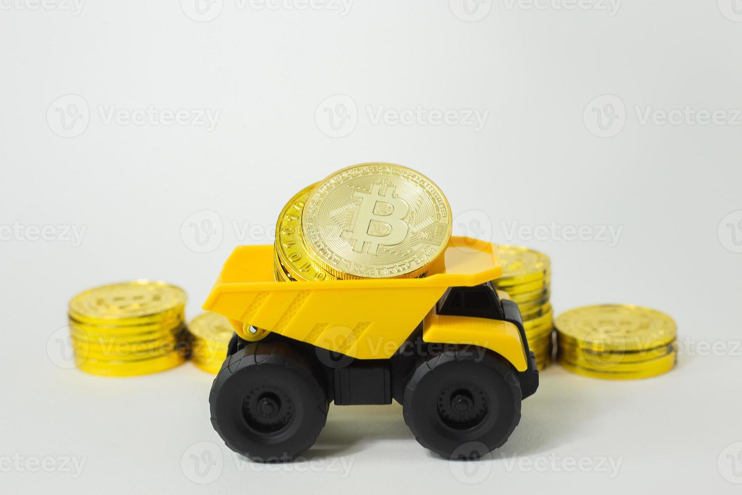 el juguete amarillo del camión volquete aisló el concepto de bitcoin sobre fondo blanco. foto