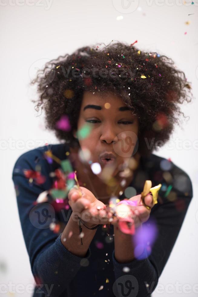 mujer afroamericana soplando confeti en el aire foto