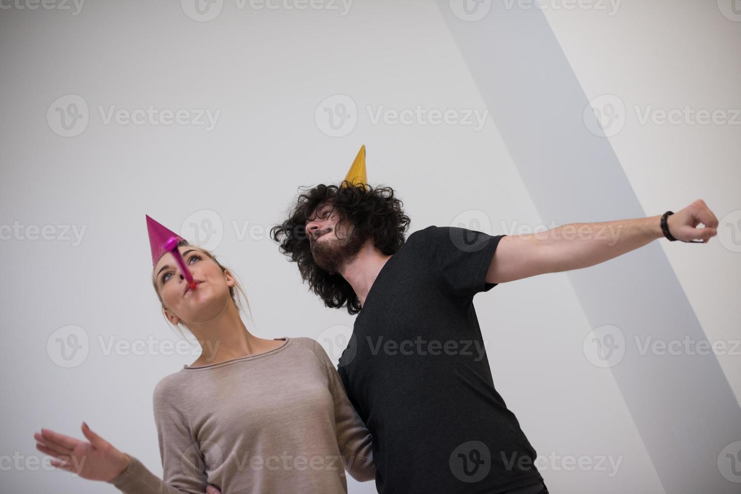 pareja en sombreros de fiesta soplando en silbato foto