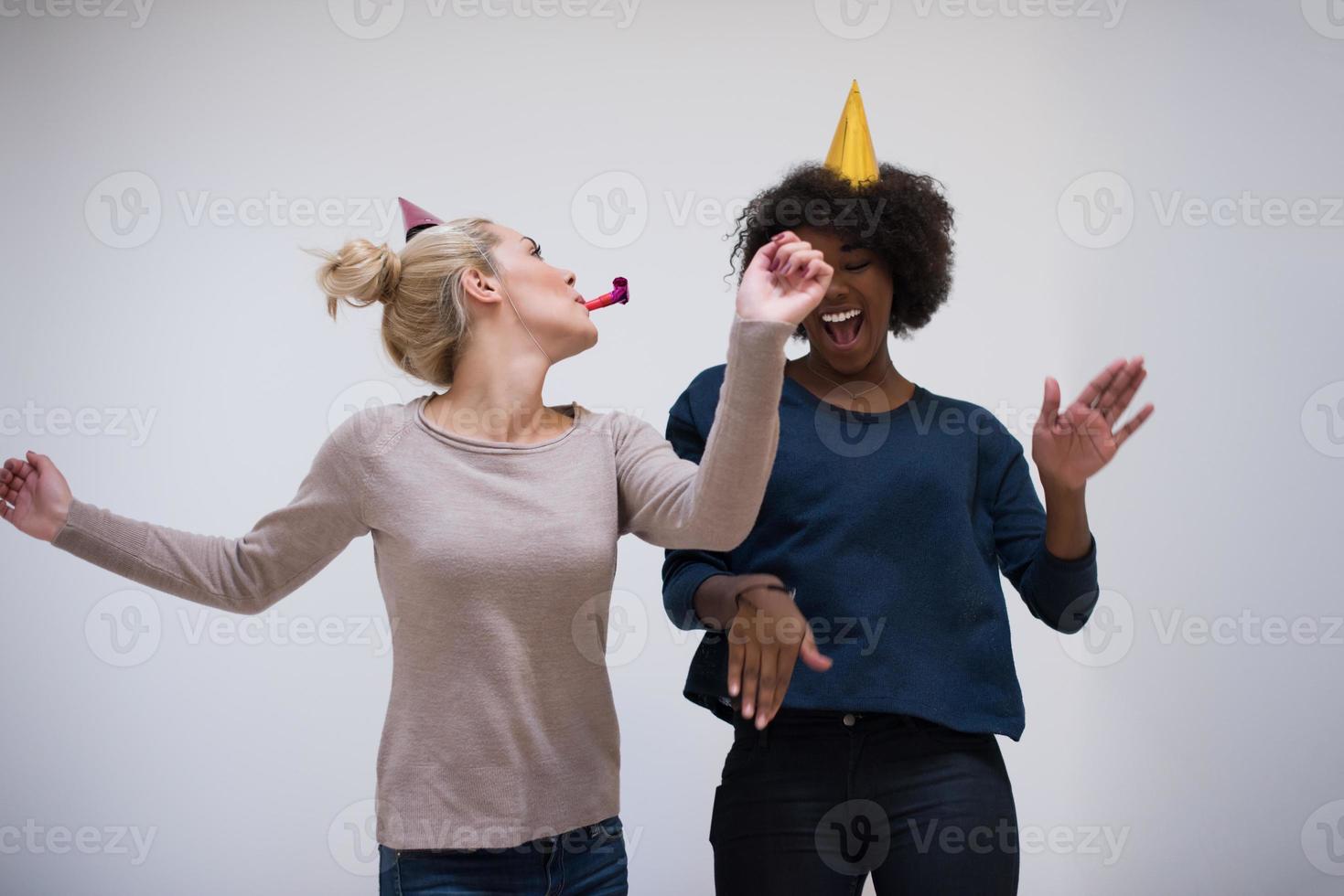 smiling women in party caps blowing to whistles photo