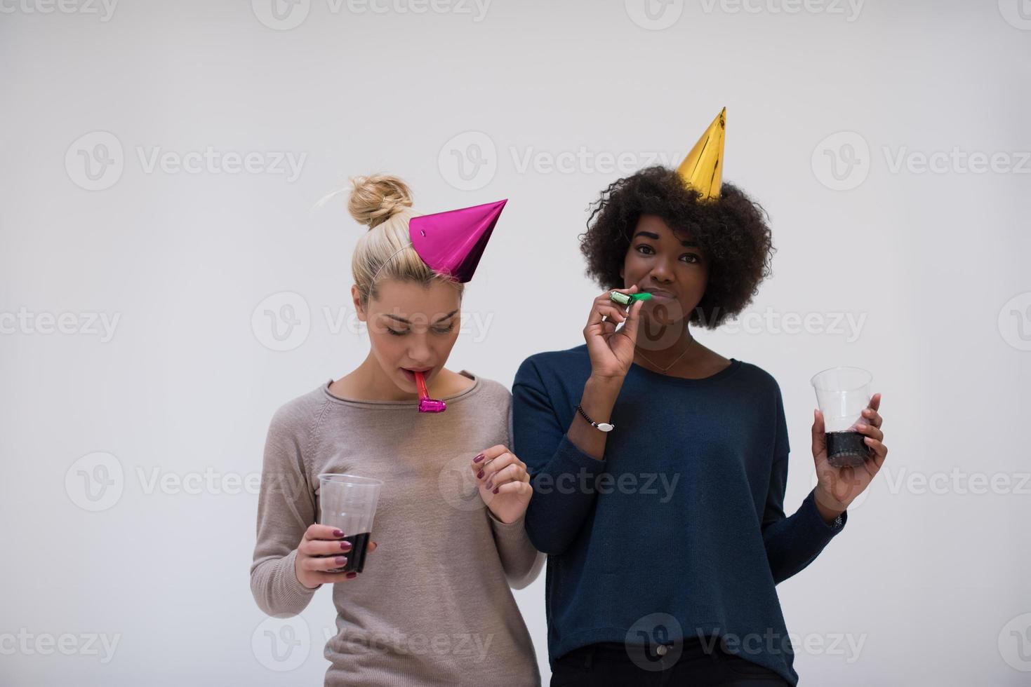 smiling women in party caps blowing to whistles photo