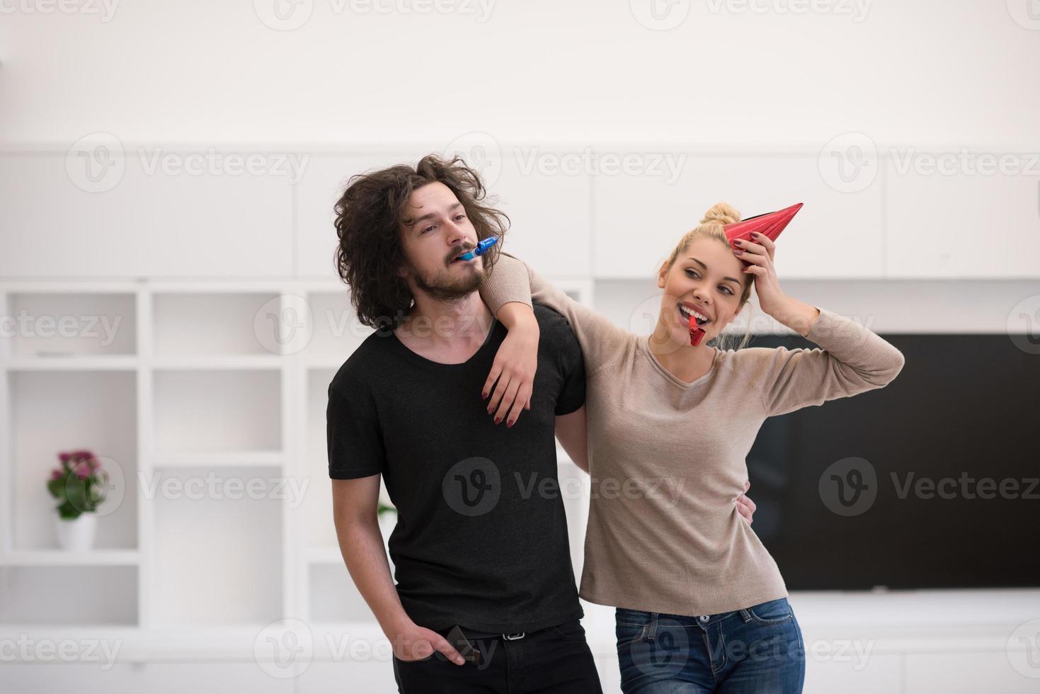 couple in party hats blowing in whistle photo