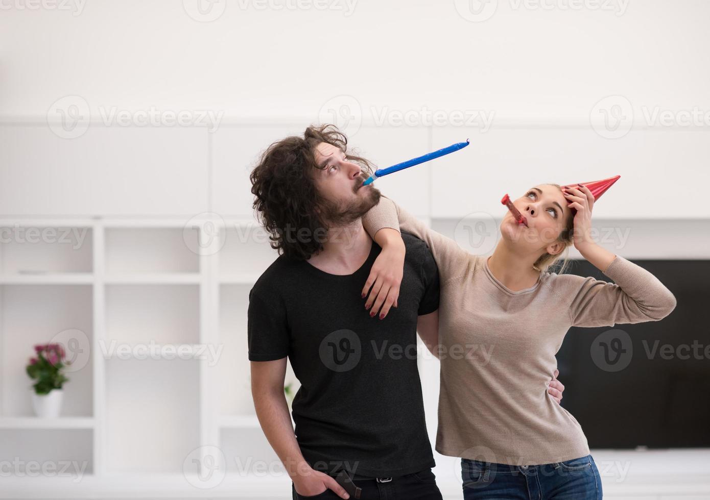 couple in party hats blowing in whistle photo