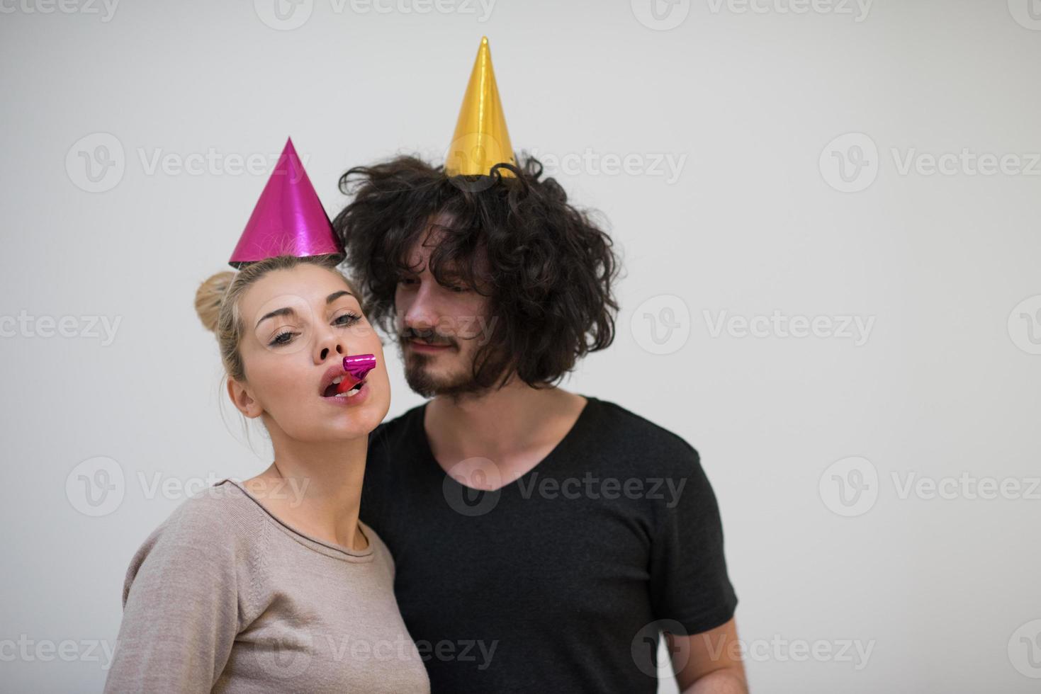 pareja en sombreros de fiesta soplando en silbato foto