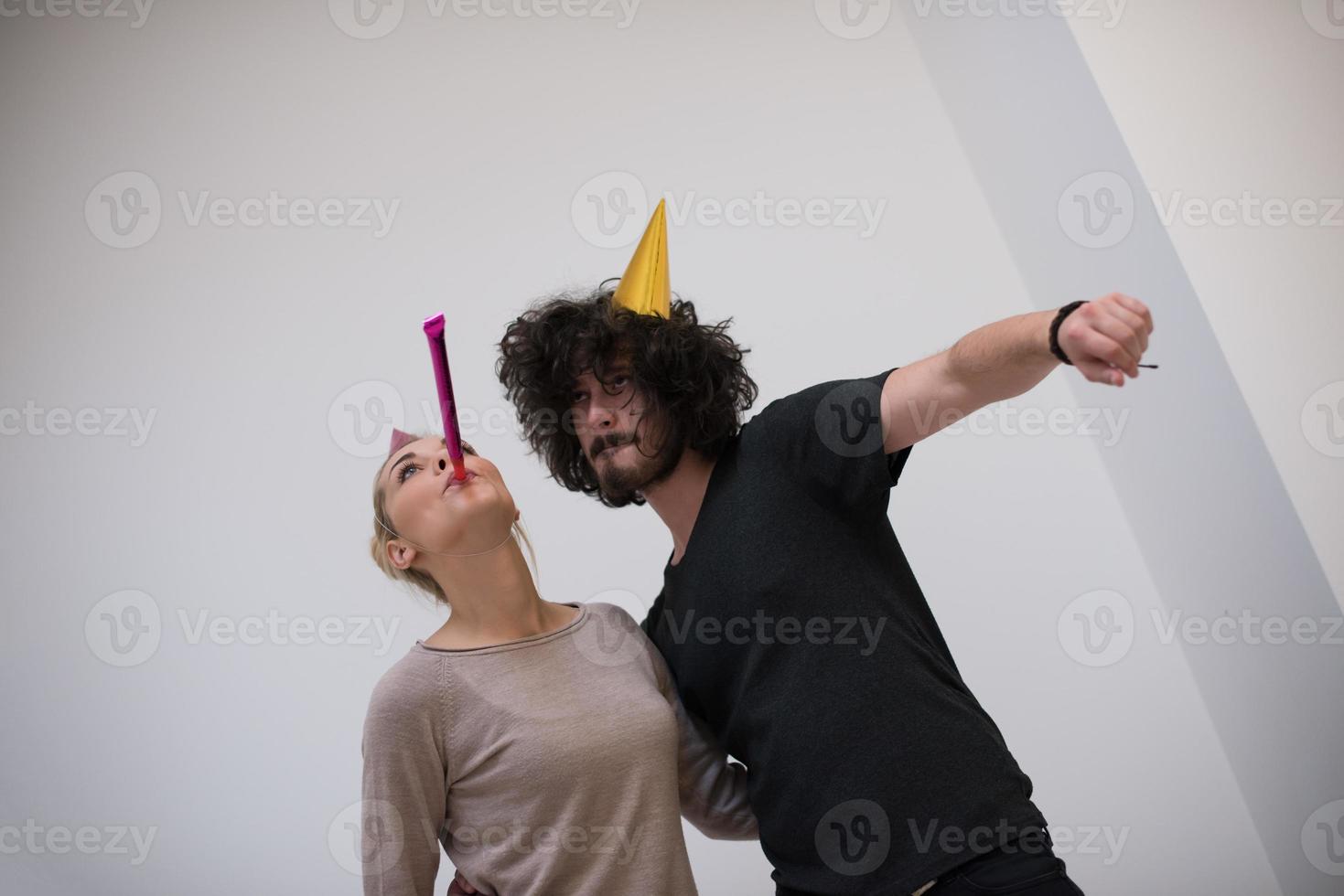 pareja en sombreros de fiesta soplando en silbato foto