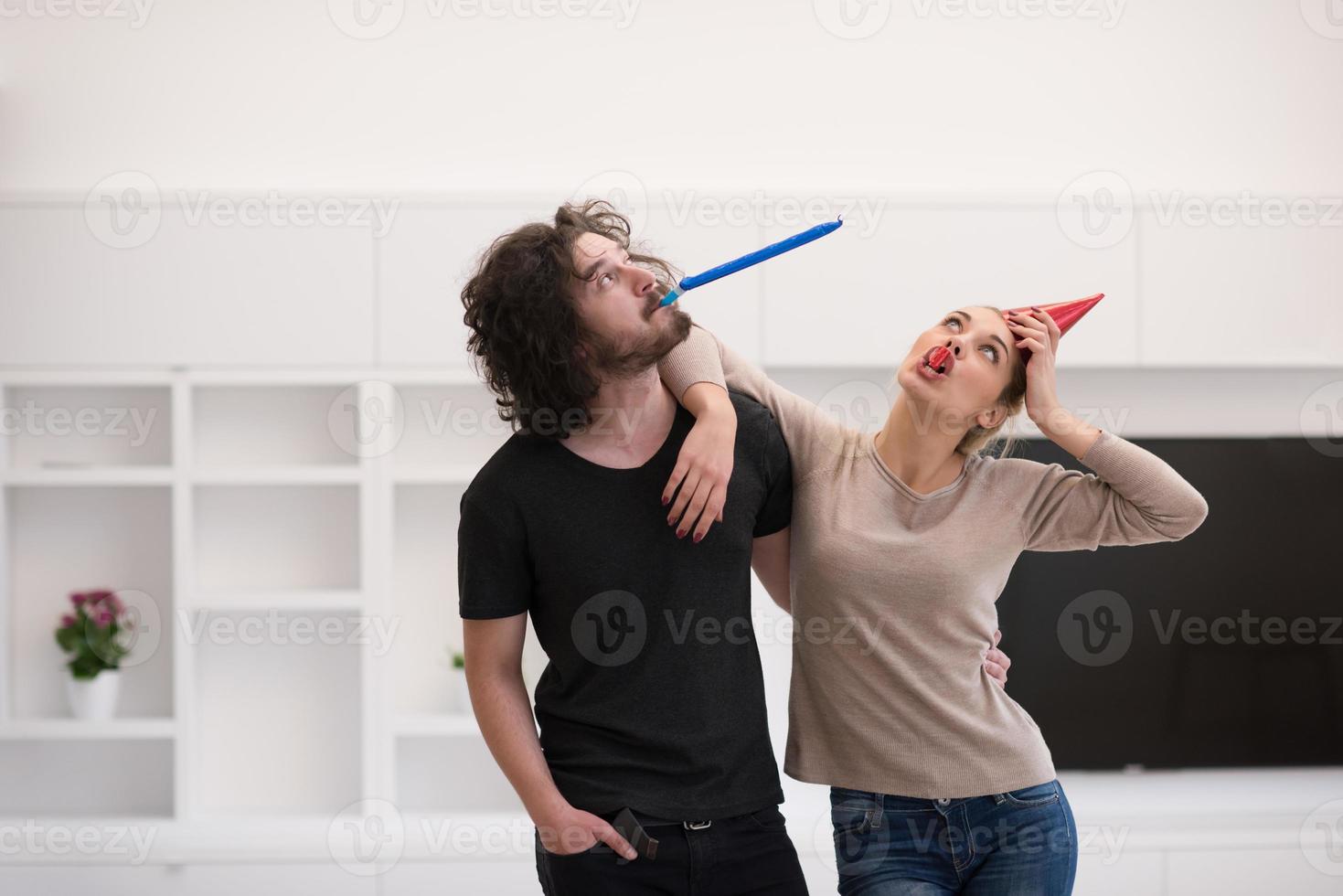 couple in party hats blowing in whistle photo