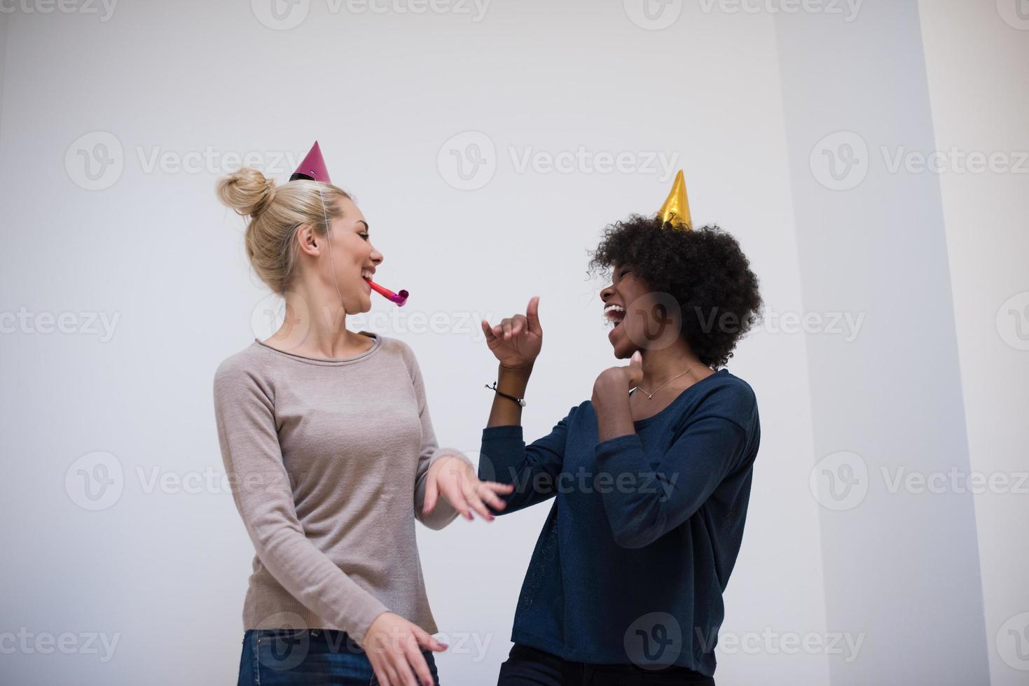 mujeres sonrientes con gorras de fiesta que soplan silbatos foto