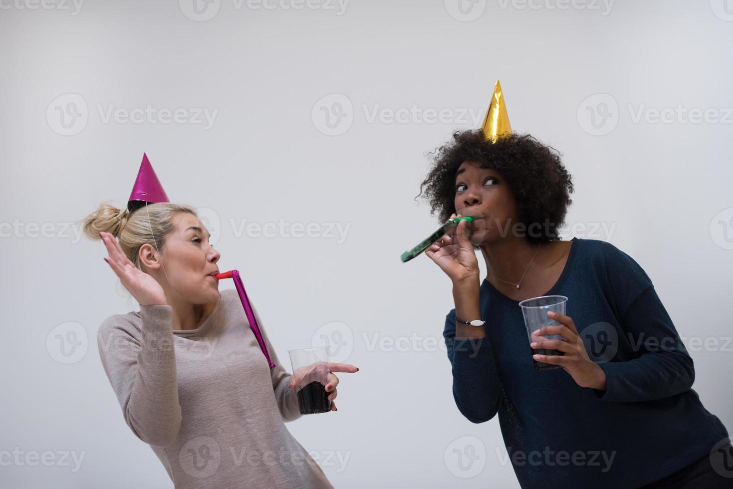 smiling women in party caps blowing to whistles photo