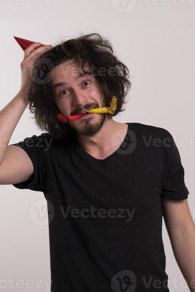 Portrait of a man in party hat blowing in whistle photo