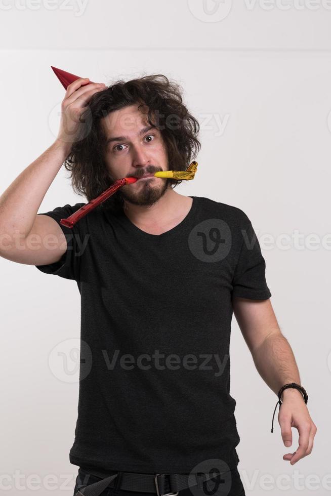 Portrait of a man in party hat blowing in whistle photo