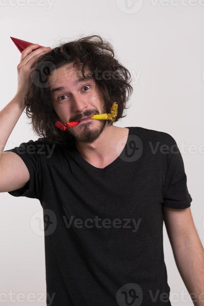 Portrait of a man in party hat blowing in whistle photo