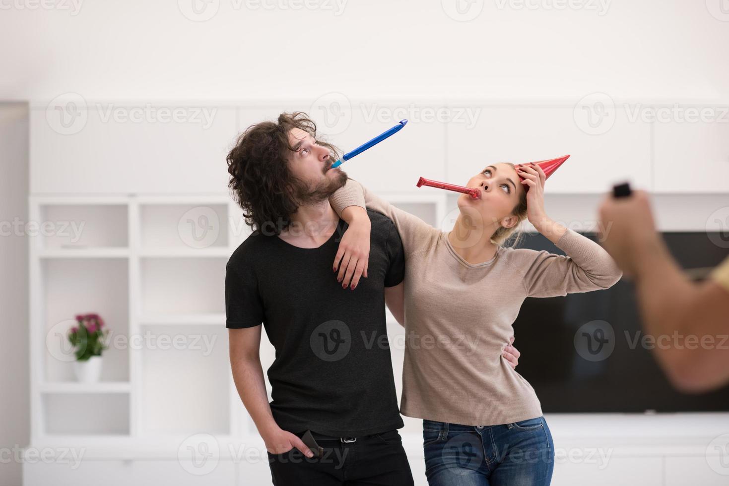 couple in party hats blowing in whistle photo