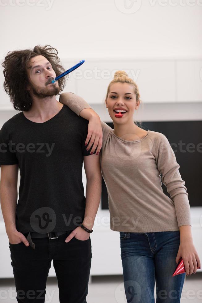 couple in party hats blowing in whistle photo