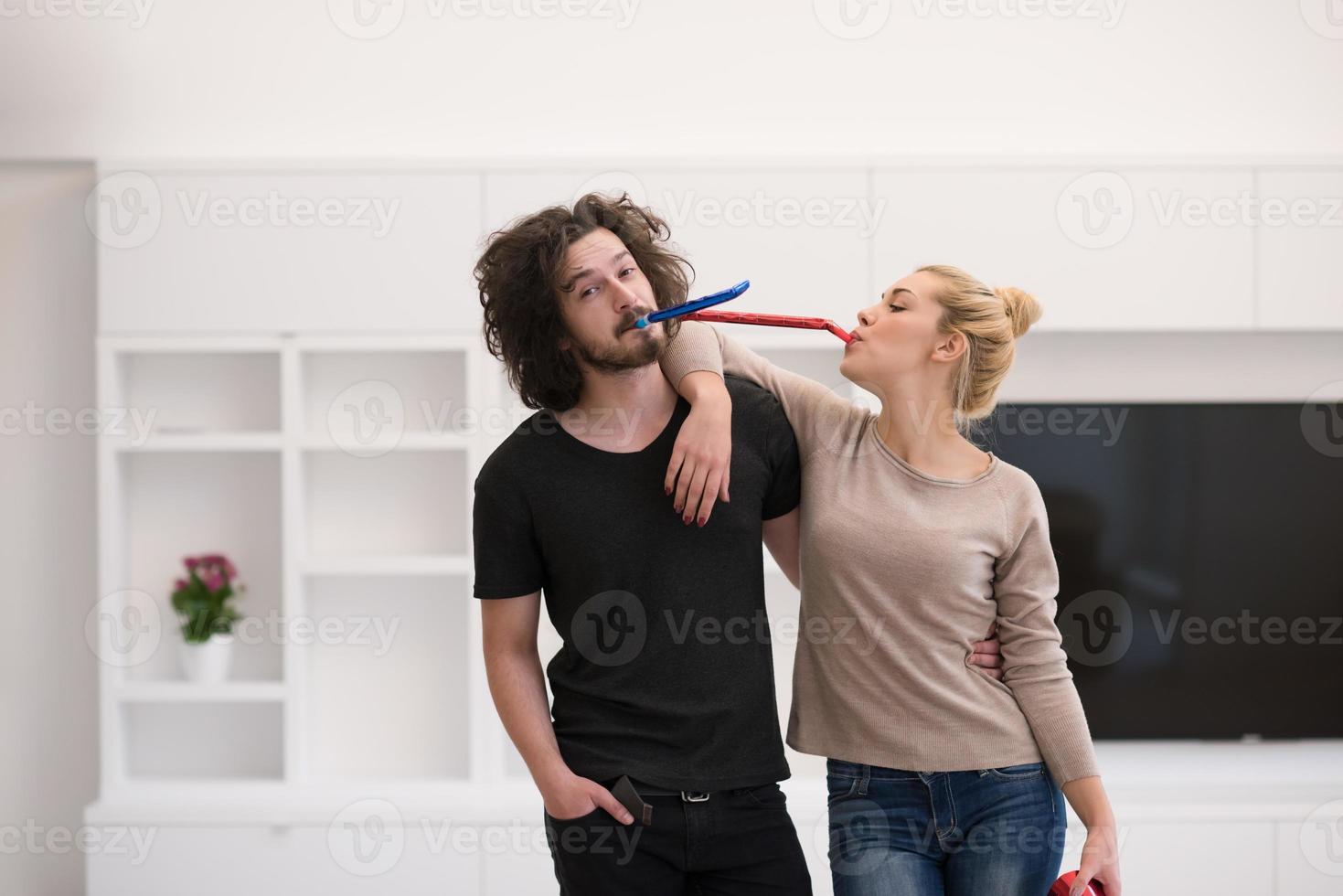 couple in party hats blowing in whistle photo