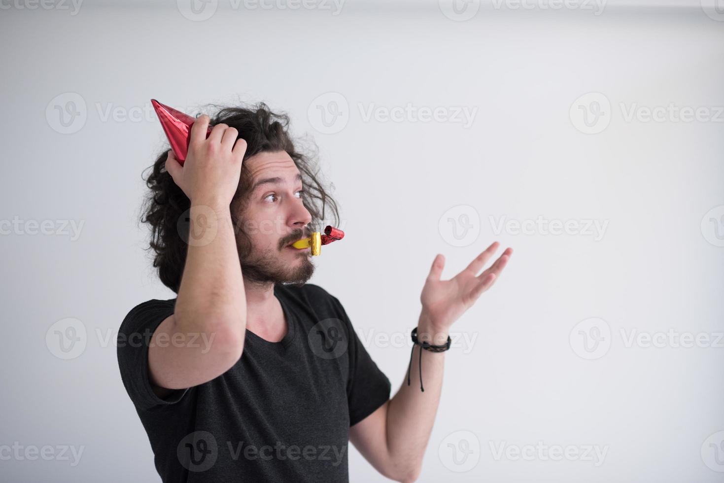 Portrait of a man in party hat blowing in whistle photo