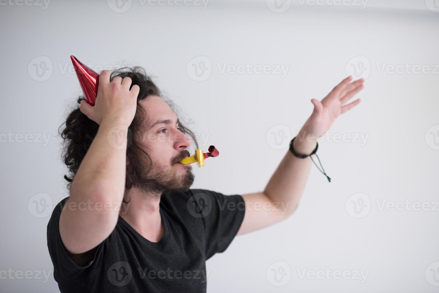 Portrait of a man in party hat blowing in whistle photo