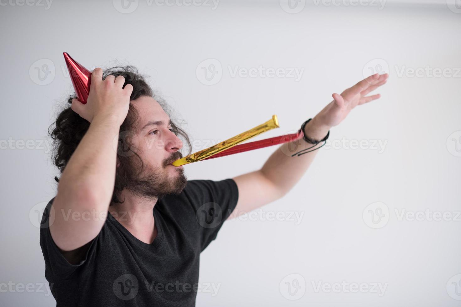 Portrait of a man in party hat blowing in whistle photo