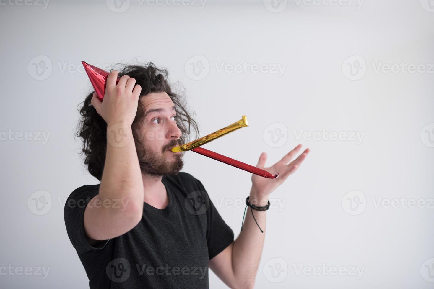 Portrait of a man in party hat blowing in whistle photo