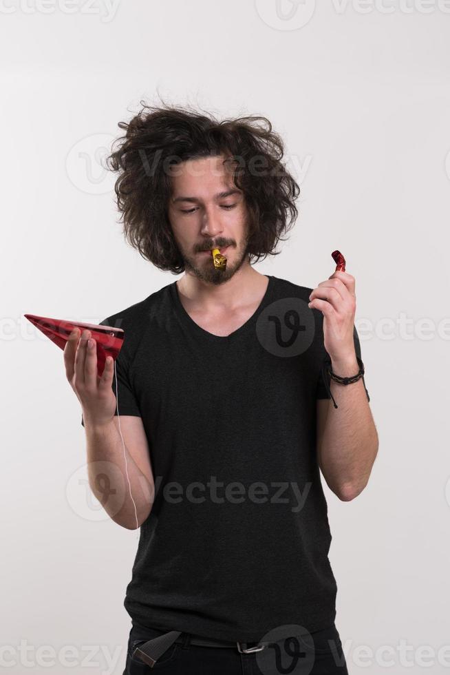 Portrait of a man in party hat blowing in whistle photo