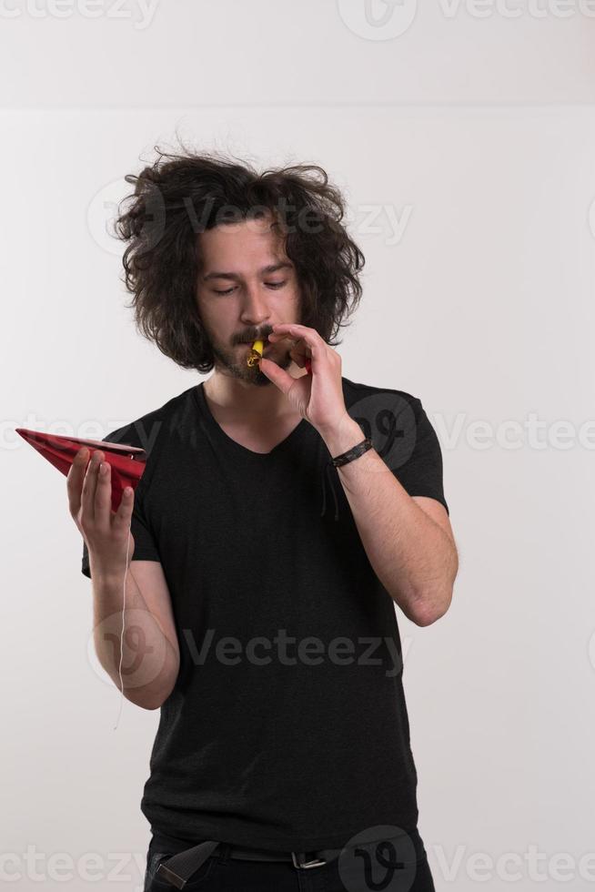 Portrait of a man in party hat blowing in whistle photo