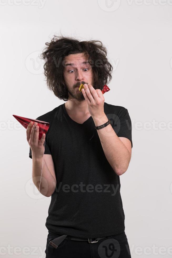 Portrait of a man in party hat blowing in whistle photo