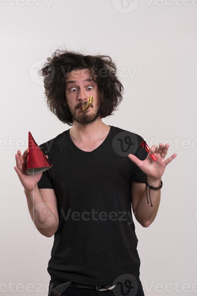 Portrait of a man in party hat blowing in whistle photo
