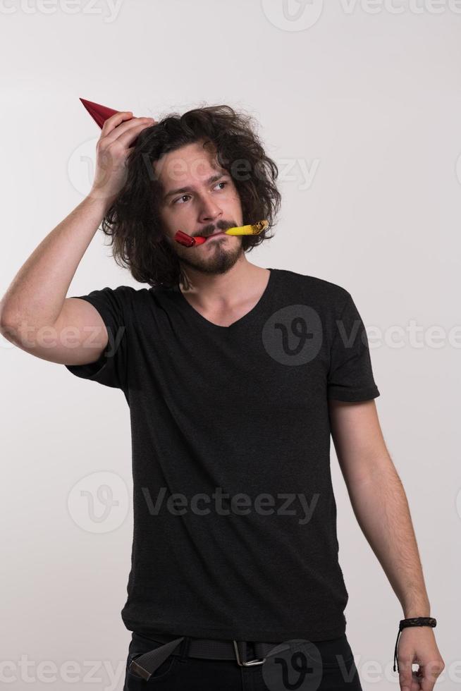 Portrait of a man in party hat blowing in whistle photo