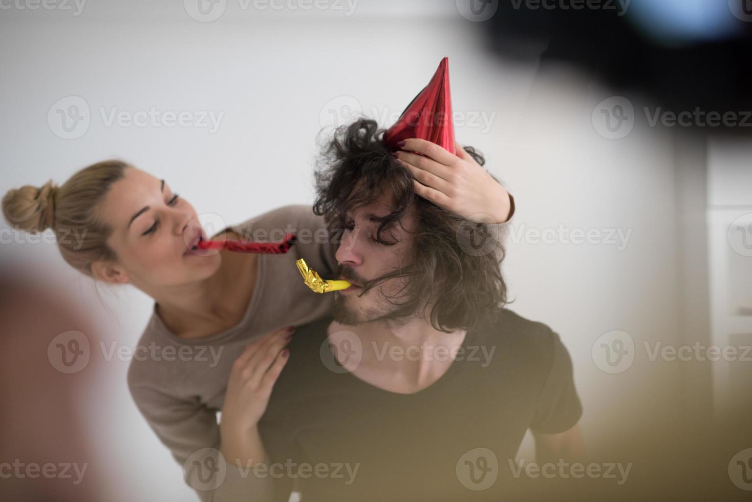 couple in party hats blowing in whistle photo