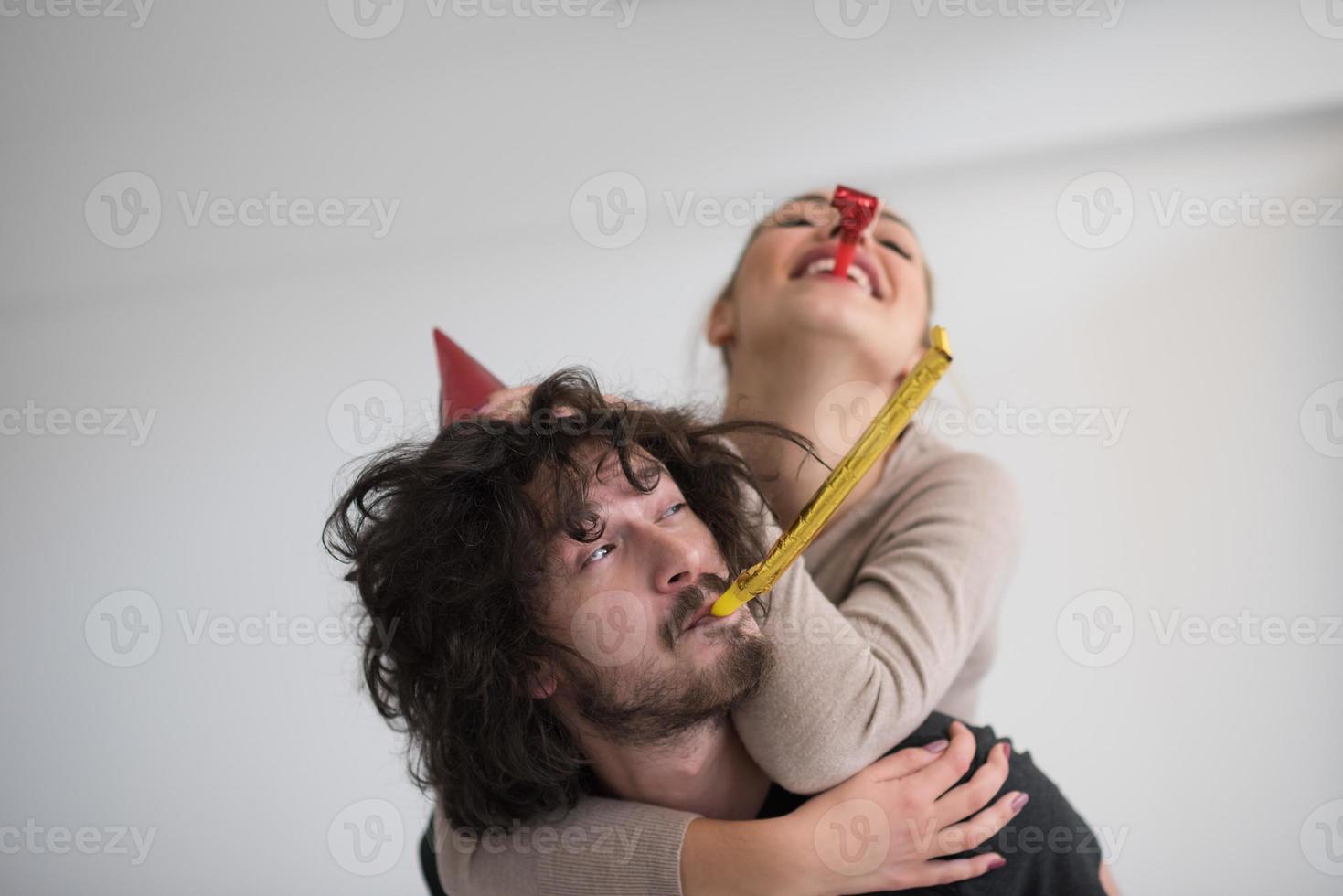 couple in party hats blowing in whistle photo