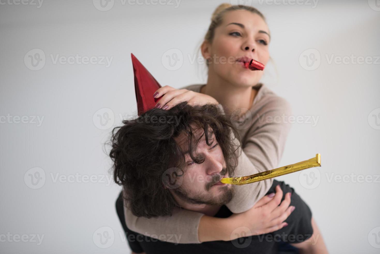 couple in party hats blowing in whistle photo