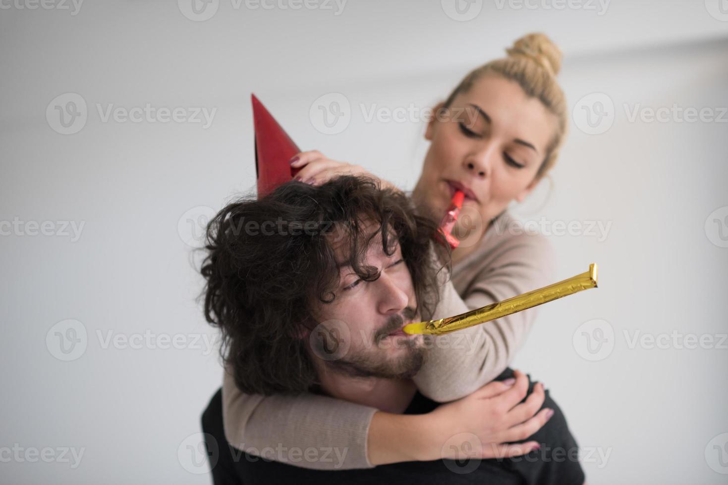 pareja en sombreros de fiesta soplando en silbato foto