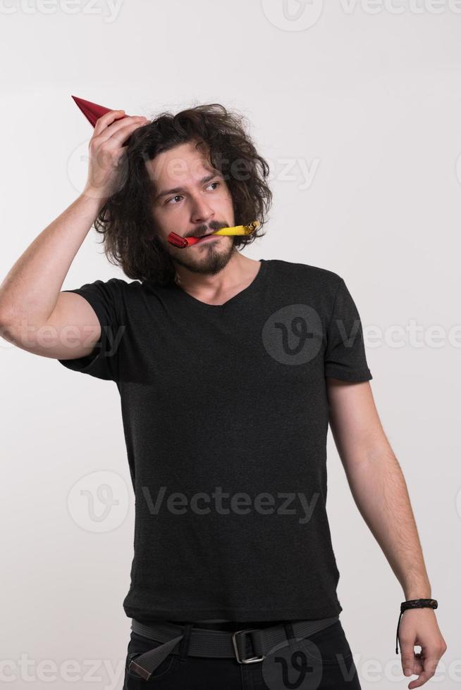 Portrait of a man in party hat blowing in whistle photo