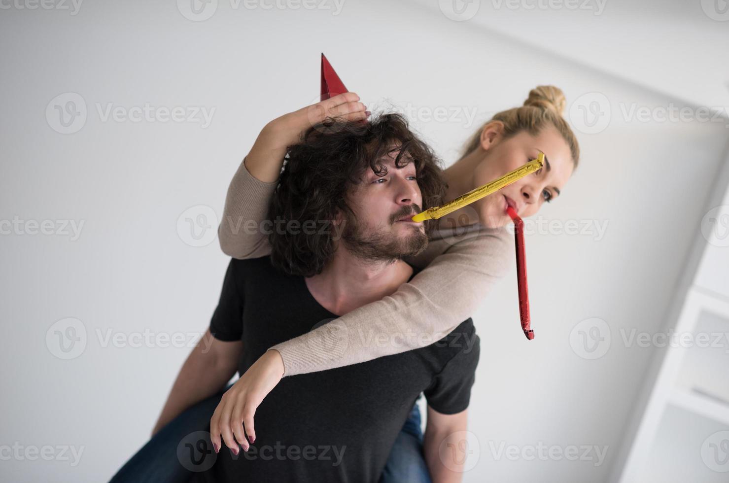 couple in party hats blowing in whistle photo