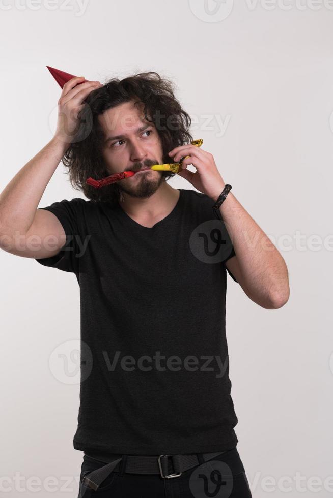 Portrait of a man in party hat blowing in whistle photo
