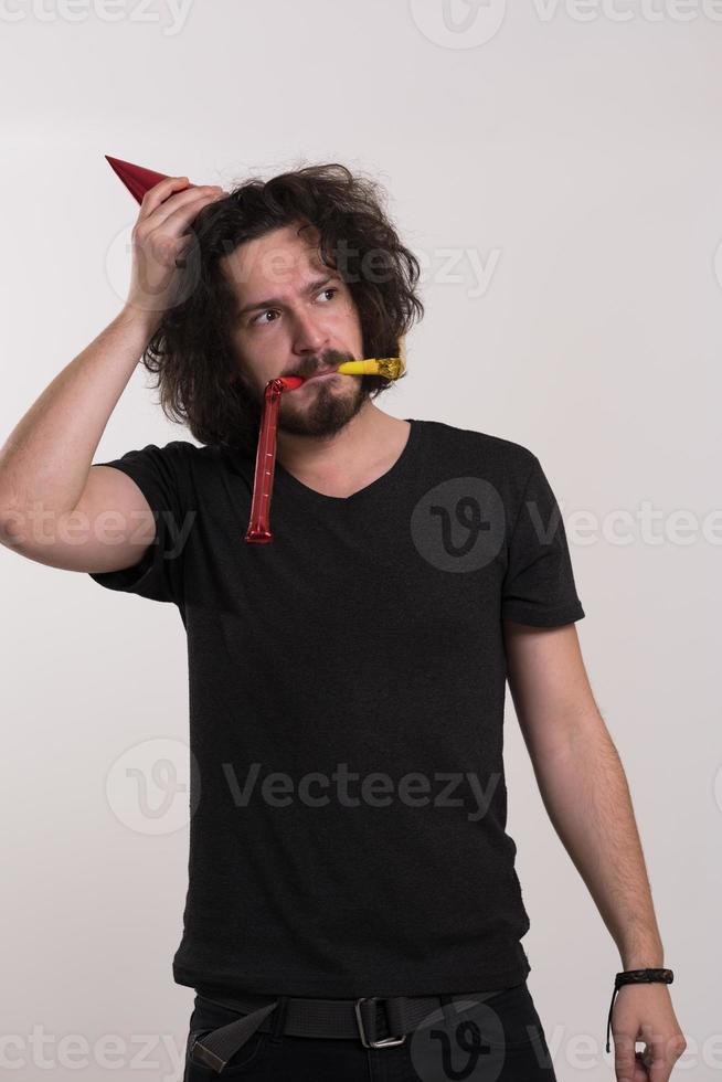Portrait of a man in party hat blowing in whistle photo