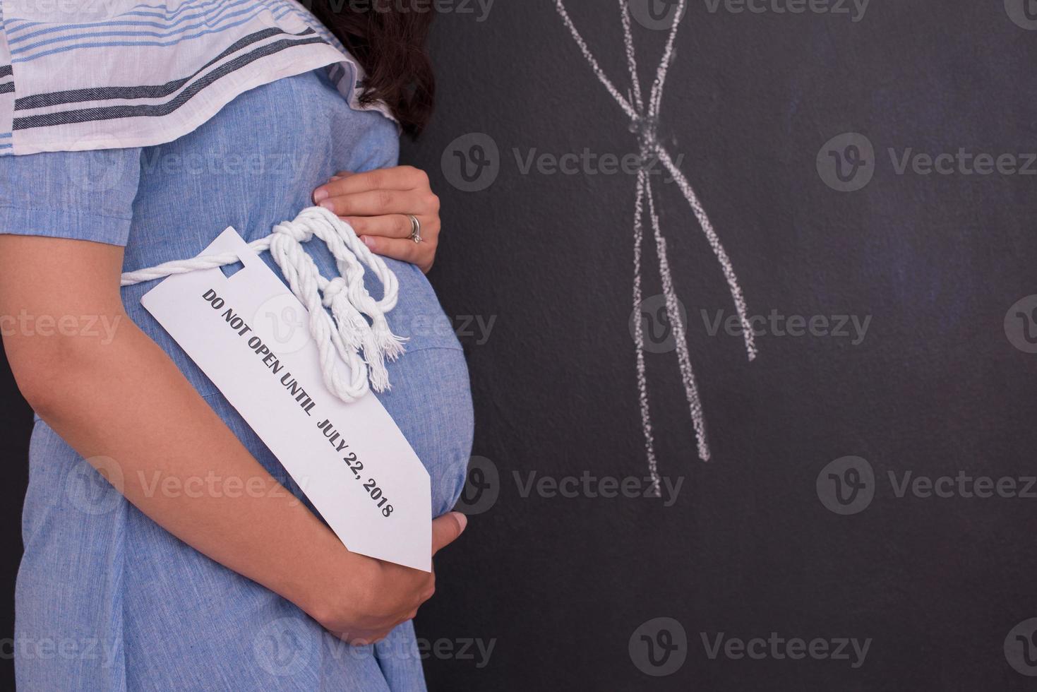 Portrait of pregnant woman in front of black chalkboard photo