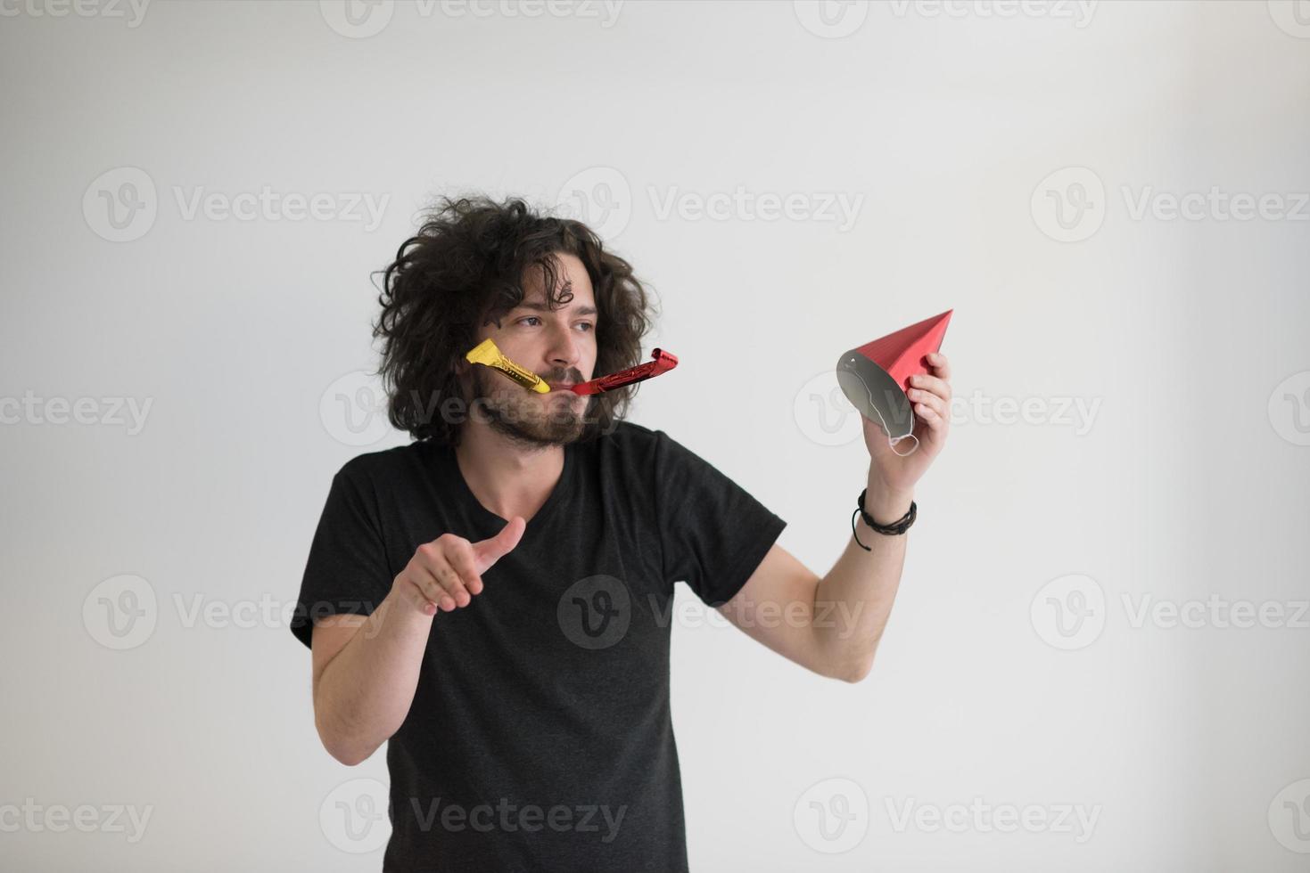 Portrait of a man in party hat blowing in whistle photo