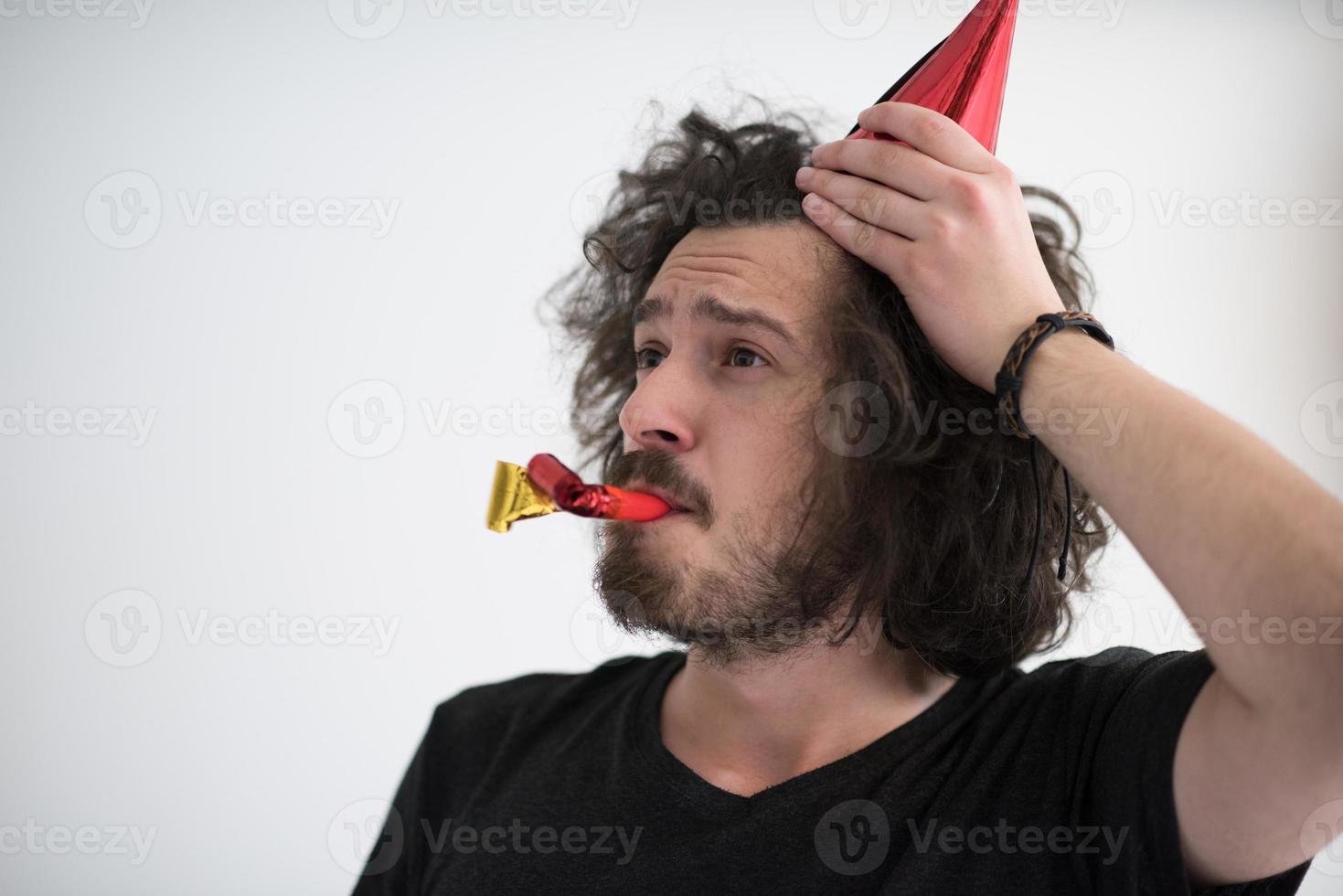 Portrait of a man in party hat blowing in whistle photo