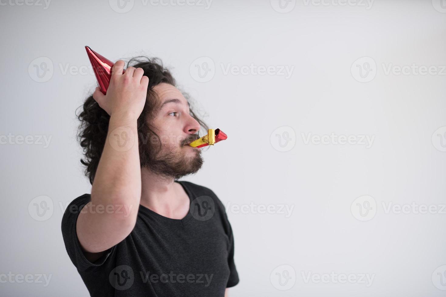 Portrait of a man in party hat blowing in whistle photo