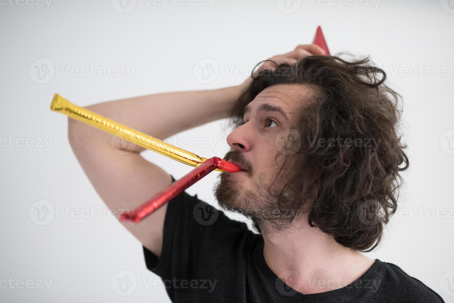 Portrait of a man in party hat blowing in whistle photo