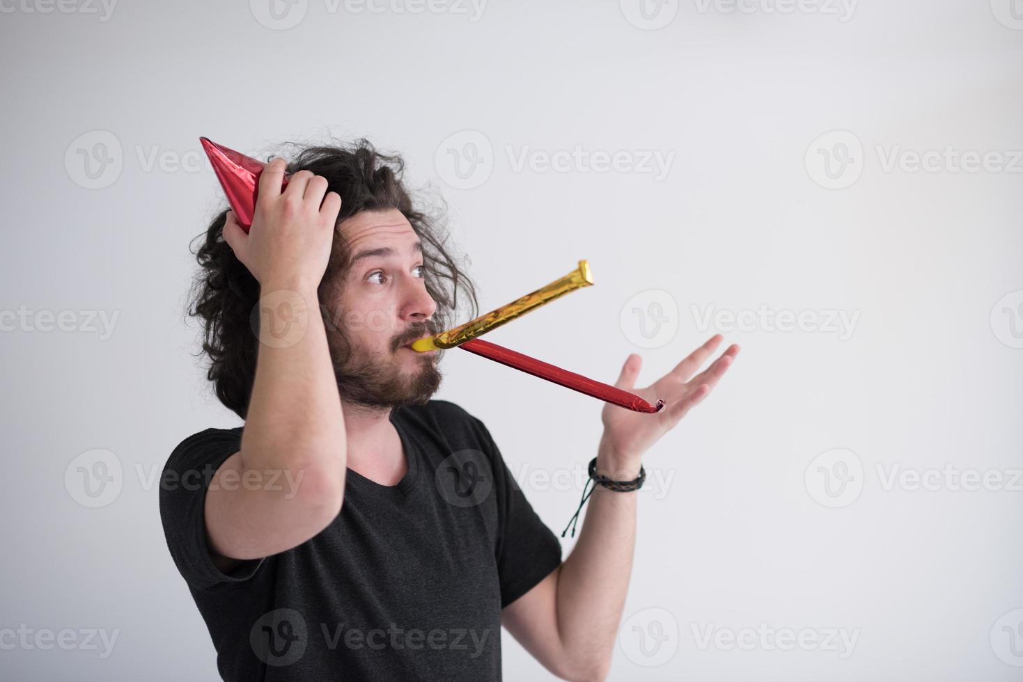 Portrait of a man in party hat blowing in whistle photo