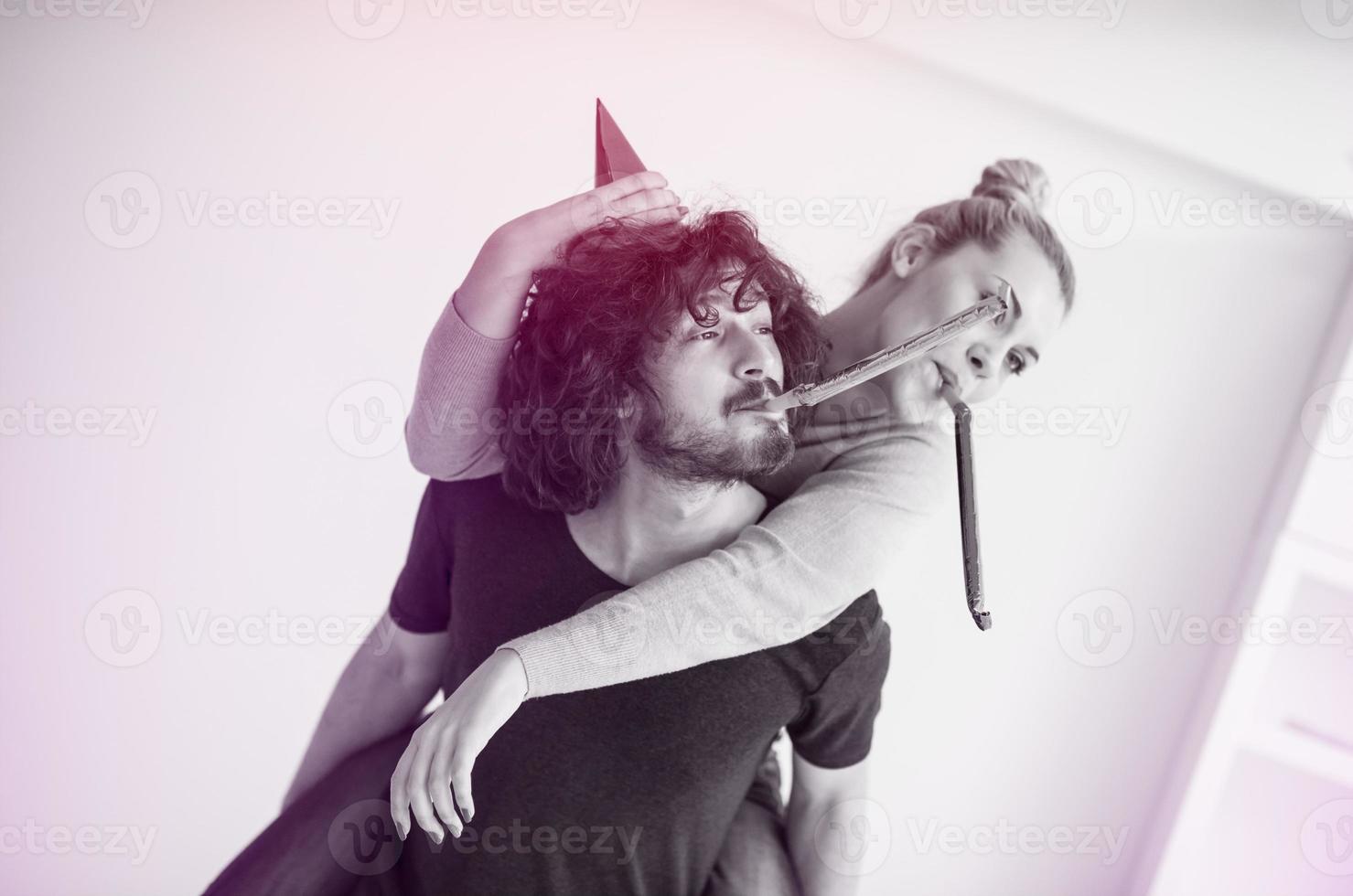 couple in party hats blowing in whistle photo