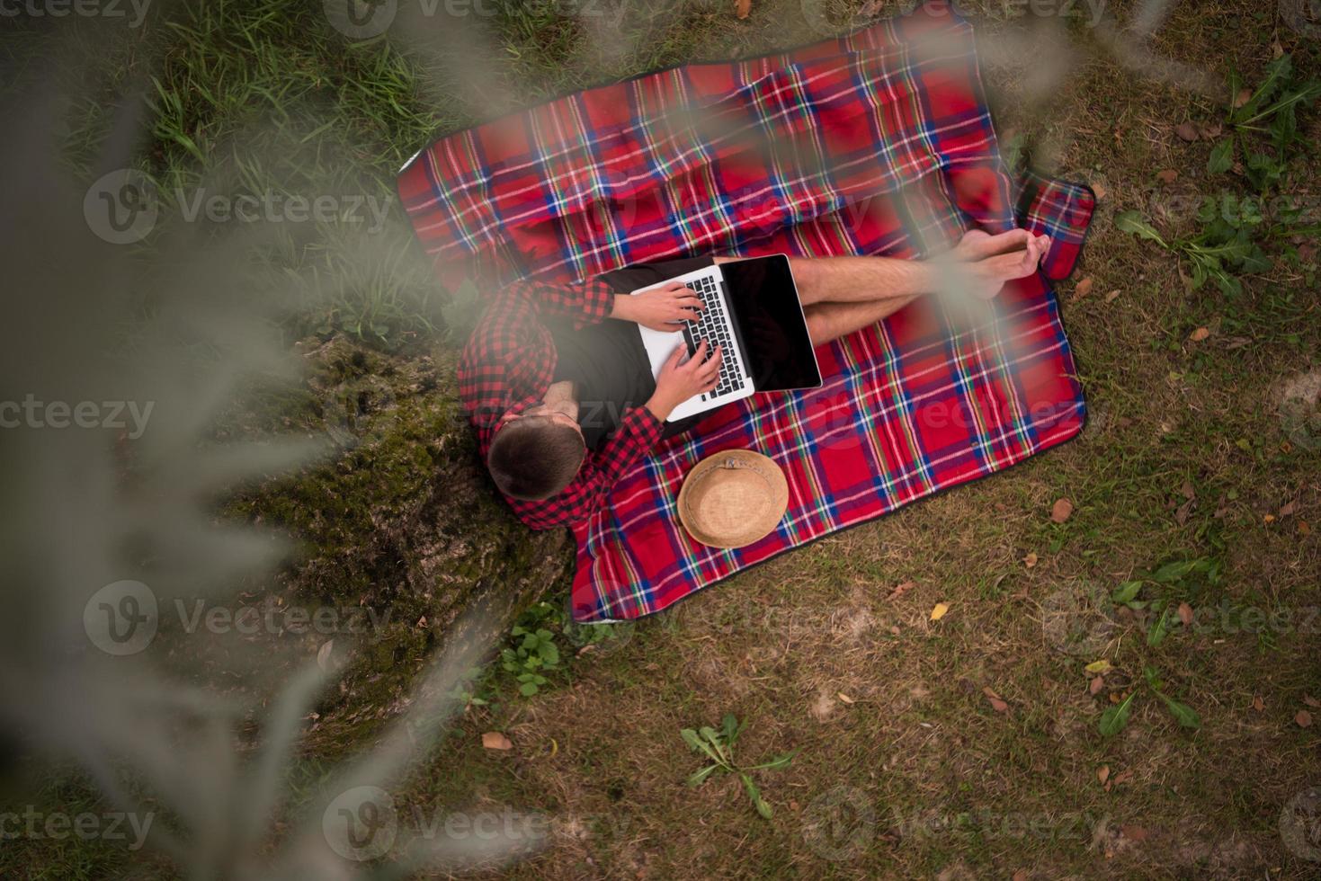 top view of man using a laptop computer under the tree photo