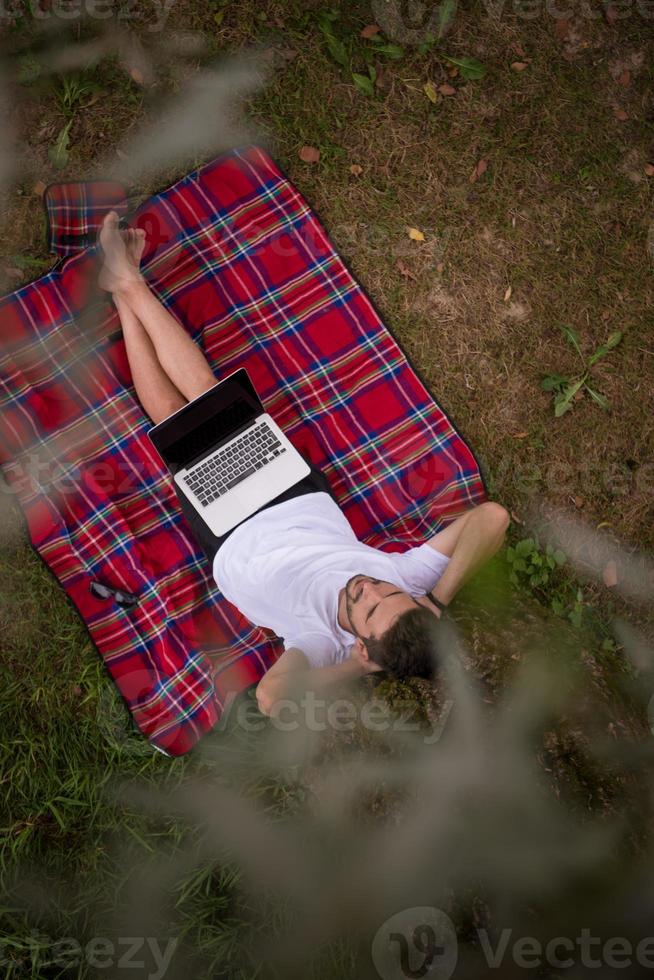 top view of man using a laptop computer under the tree photo