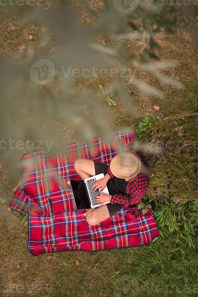 top view of man using a laptop computer under the tree photo